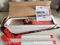Photo showing white kids hockey goal net frame, orange foam puck, two CCM JetSpeed mini hockey sticks with orange blades, instruction manual and orange netting in box.