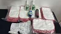 The full lot of cleaning cloths, hand sanitizers, cleaning brushes, and other cleaning products laid out on a black surface, showing quantity and condition.