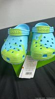 Front view of light blue and lime green kids Crocs size 12 on box with tag attached