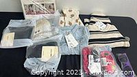 Photo shows multiple new children's clothing items including jeans, sweaters, beanie hats, sunglasses, and shoes all laid out on a table.