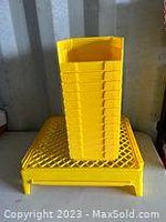 Yellow plastic tool storage bins stacked neatly on a yellow plastic rack.