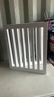 Side view of one white wooden pet gate panel with vertical slats