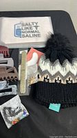 Lot contents showing hair clips, knit hat, and other small items on black surface