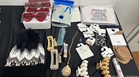Overview of the lot with various new women's accessories including hat, hair claws, jewelry, skincare tube, and socks on black surface.