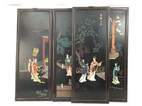 Front view of set of four black lacquer Koromandel panels with scenes of young women outside, framed in dark wood with brass hangers.