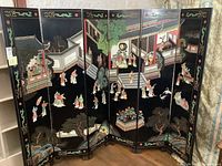 Full front view showing six hinged panels with carved and painted maidens in garden scenes.