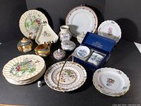 Full set overview showing all pieces arranged on a black surface, flower-patterned plates with various shapes and sizes, small porcelain serving and decorative accessories.