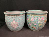 Front view of both large ceramic fish bowls showing different detailed painted floral and fish designs.