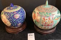 Both ginger jars with lids on wood stands, front view