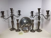 Overall group shot: two candlesticks, two candelabras, plate, dish, and napkin rings arranged