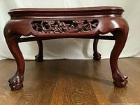 Front low angle view showing the curved legs ending in ball and claw feet and detailed apron carving.