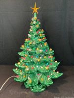 Full front view of the green glazed ceramic Christmas tree with powered multi-colored bulbs and amber star topper