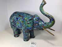 Front and side view of vintage cloisonné brass and enamel elephant figurine showing colorful pattern and raised trunk.