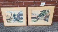 Photo of two framed watercolor paintings depicting Vietnamese village scenes, showing overall artwork and frames.