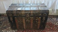 Front view of the antique steamer trunk showing metal reinforcements and worn leather or fabric straps.