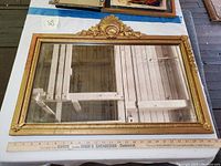 Full view of the large rectangular antique wall mirror showing ornate detailing on the frame and aged reflective surface.