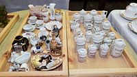 Overview of wooden trays with assorted items: lustre spice jars, animal figurines, miniature teaware