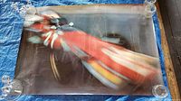 Full view of the red race car photo poster laid flat, showing overall condition and edge damage.