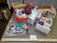 Overview of three boxes and one plastic bag filled with loose sports trading cards of various brands and years.