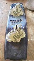 Top view of Mission Neptune 135 wakeboard with white and gray bindings attached, showing the full board and branding