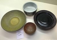 Four assorted pottery dishes including a large green Royal Copenhagen bowl and three other bowls.