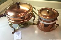 Copper chafing dish and double broiler set viewed from the side on countertop, showing tarnish and wear