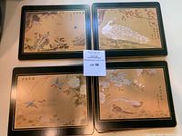 Eleven hardboard trivets arranged in four groups, each featuring different bird and floral designs with black and gold borders.