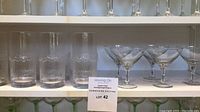 Full view of 6 textured Iittala Niva tumblers and 5 Belfor champagne glasses on shelf with lot signage