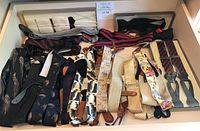 Full drawer view showing a variety of men's suspenders and bow ties laid out, revealing multiple colors and patterns.
