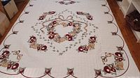 Full view of queen sized quilt showing central floral applique pattern on white background with red border and vines.