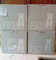 Four Riedel-branded boxes stacked with one wine glass in front