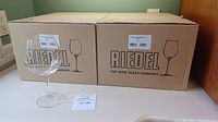 Two sealed Riedel boxes with one glass in front