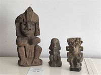 Three stone statues on white surface, showing the relative size and details of each figurative sculpture.