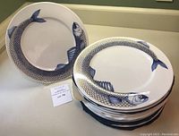 Stack of plates with one plate leaning showing fish design