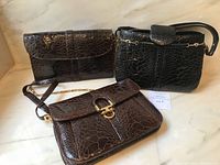 All three vintage Biller crocodile purses displayed together on a marble surface.