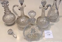 Five cut glass decanters and one loose stopper arranged on tabletop with lot card