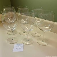 Six clear vintage Riedel crystal red wine glasses displayed upright on a white surface.