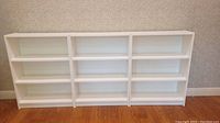 Front view of the three white Ikea Billy bookcases placed side by side showing all shelves.