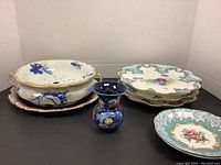 Set of Royal Doulton and Royal Albert dishes including casse role bowl, display plates, saucers and vase on neutral background