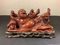 Front view of carved Laughing Buddha figure with monkeys and wooden base showing full detail of the subject.