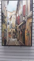 Full view of larger framed canvas painting of European street scene with red shutters and flower pots