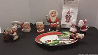 Full set of ceramic Christmas items including Father Christmas figurine, salt and pepper shakers shaped like Santa and Mrs Claus, and holiday-themed tray and other decorative pieces in background.