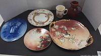 Various china display dishes including floral Royal Doulton plate, Limoges hand-painted tray and plate, Bunnykins cup, two pitchers and a blue platter.