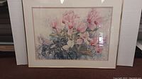 Full view of framed watercolour painting showing cyclamen pink flowers and foliage.