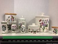 Photo showing six items: three Portmeirion canisters with lids and three matching vases with floral botanical designs.