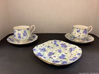 Photo showing 2 cups on saucers with floral pattern and 1 side plate in front