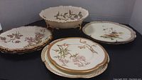 Overall view of footed bowl and six plates in various floral patterns