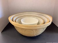 Set of 4 mixing bowls nested together showing size gradation and beige embossed pattern bowls with small white bowl inside