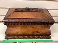 Front and side view of vintage carved wood box with floral carvings and lock on front.