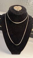 Front view of 15.5 inch sterling silver flat snake chain necklace and heart pendant on black display.